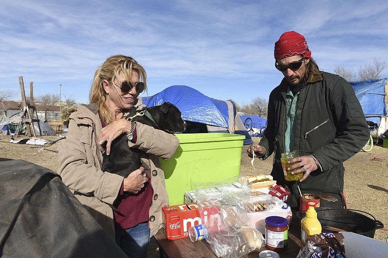 Camp founder Amanada Hunter, left, holds "Maximus" a three-month old puppy as Erik Benroth makes lunch at the tent camp near Hughes and N.W. 1st Avenue Wednesday, Jan. 3, 2017.