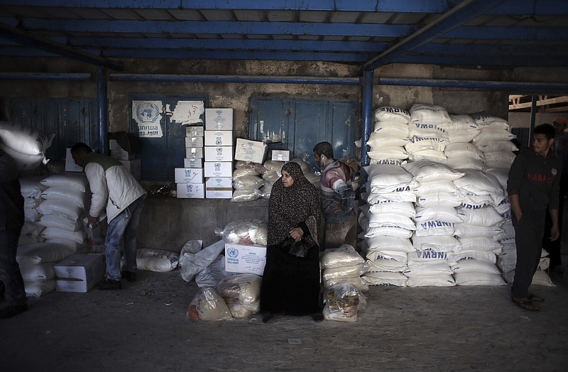 In this Sunday Jan. 14, 2018 photo, a Palestinian woman waits to receive food aid at a U.N. warehouse in the Shati refugee camp, Gaza City. From the Gaza Strip to Jordan and Lebanon, millions of Palestinians are bracing for the worst as the Trump administration moves toward cutting funding to the U.N. agency that assists Palestinian refugees across the region. The expected cuts could deliver a painful blow to some of the weakest populations in the Middle East and risk destabilizing the already struggling countries that host displaced Palestinian refugees and their descendants. (AP Photo/ Khalil Hamra)