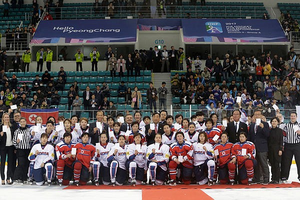 In this April 6, 2017, file photo, women's ice hockey players of South Korea (in white) and North Korea (in red) pose for a photo with International Ice Hockey Federation officials after their Ice Hockey Women's World Championship Division II Group A game in Gangneung, South Korea.