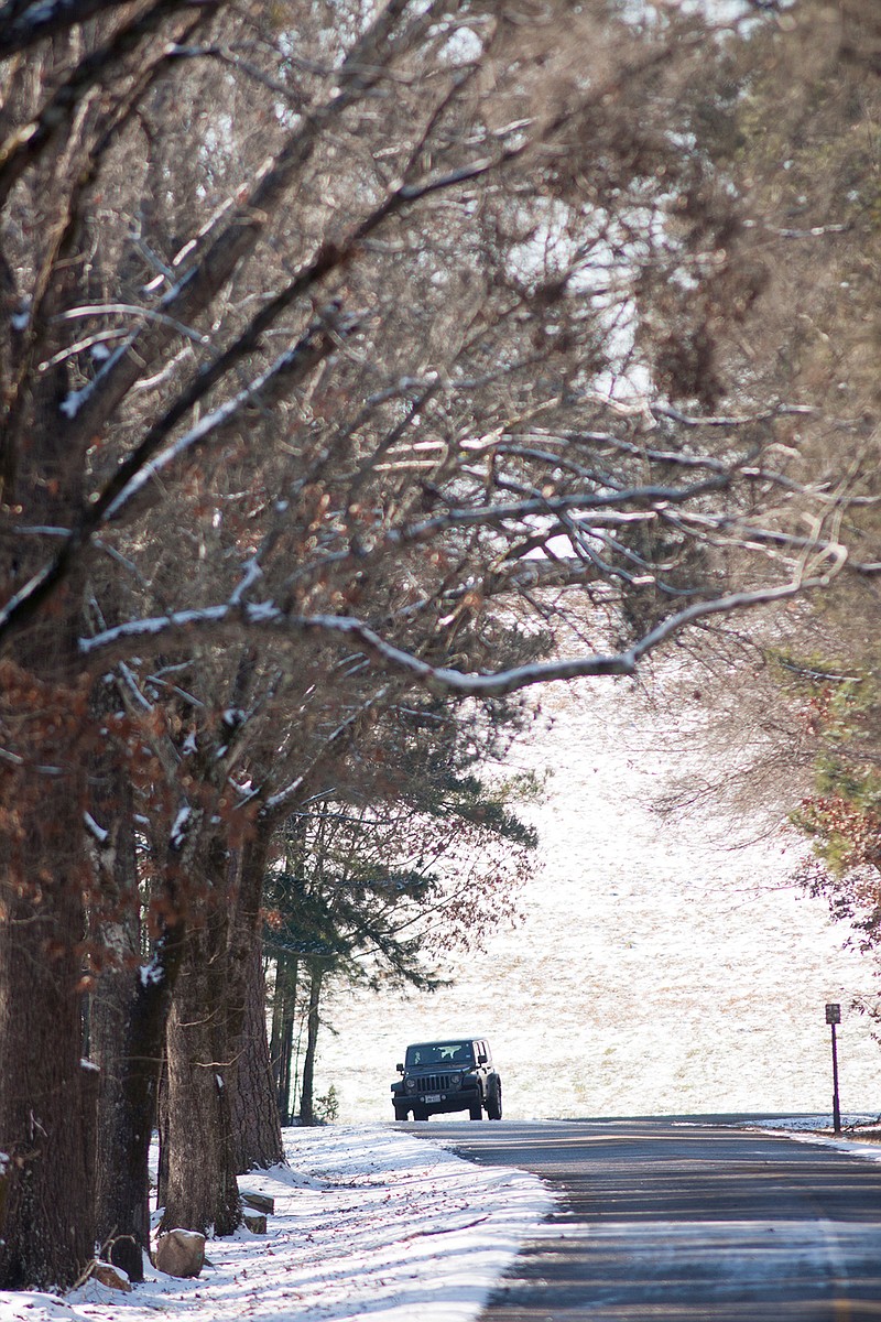 A Jeep navigates the partially frozen Park Road Tuesday near the Wright Patman Lake Dam. Any snow or ice melted by sunshine Tuesday was expected to refreeze as night fell, causing officials to recommend staying off the roads again today.