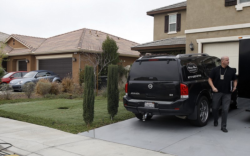 Detective walks next to a home Tuesday, Jan. 16, 2018, where police arrested a couple on Sunday accused of holding 13 children captive, in Perris, Calif. Authorities said an emaciated teenager led deputies to the California home where her 12 brothers and sisters were locked up in filthy conditions, with some of them malnourished and chained to beds. (AP Photo/Alex Gallardo)