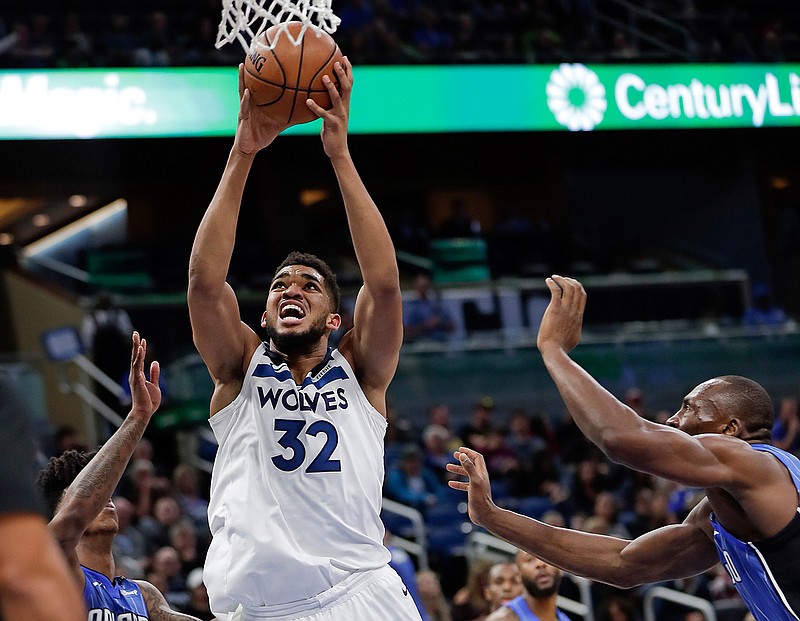 Minnesota Timberwolves' Karl-Anthony Towns makes a shot as he gets between Orlando Magic's Elfrid Payton, left, and Bismack Biyombo, right, during the first half of an NBA basketball game, Tuesday, Jan. 16, 2018, in Orlando, Fla. 