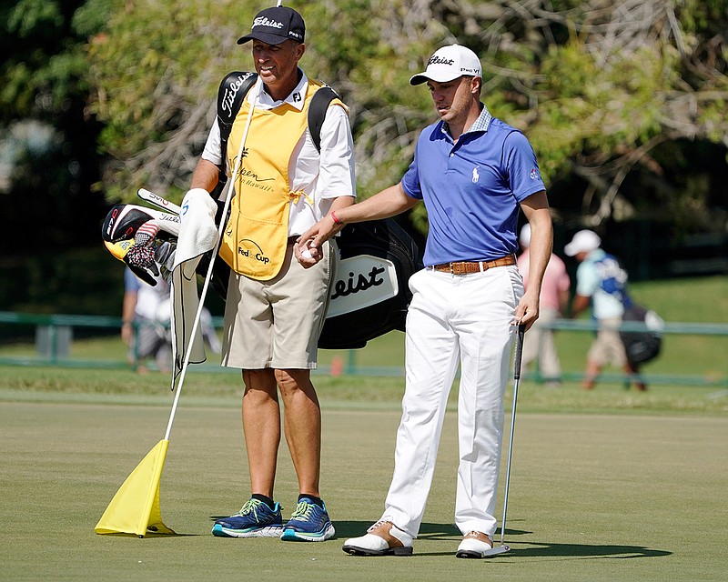 Jim "Bones" Mackay, left, takes the ball from Justin Thomas on the seventh green during the third round of the Sony Open golf tournament, Saturday Jan. 13, 2018, in Honolulu. Although he retired last year, MacKay is filling in for Thomas' injured caddie at the Sony Open. 