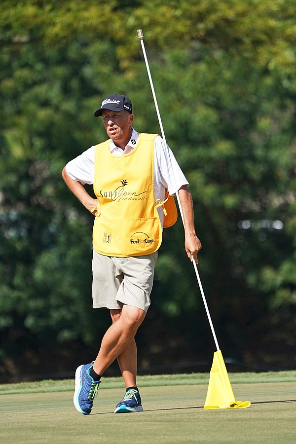 While leaning on the pin flag, Jim "Bones" Mackay stands on the seventh green during last Saturday's third round of the Sony Open in Honolulu. Although he retired last year, MacKay filled in for Justin Thomas' injured caddie.