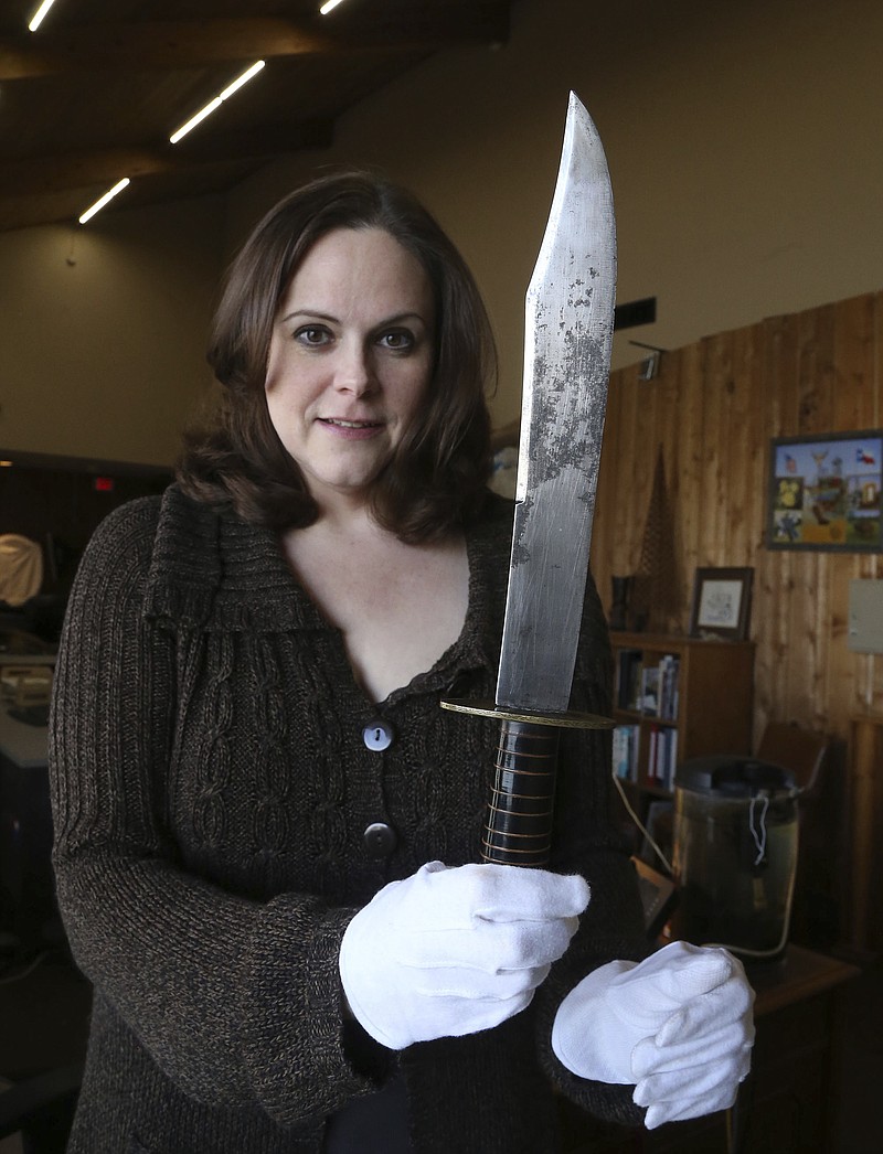 In this Jan. 9, 2018 photo, Shelly Crittendon, artifacts and exhibits manger, holds up a 17-inch Bowie knife recently donated to the Texas Ranger Hall of Fame Museum, Tuesday, Jan. 9, 2018, in Waco, Texas. The knife's scabbard gives a tantalizing sign of its true significance. Engraved in a flowery script are the words: "R.P. Bowie to Capt. Wm. Y. Lacey." That would appear to be Rezin Pleasant Bowie, Jim's big brother, who helped popularize the Bowie knife in the 1830s and was known for giving them as gifts. (Rod Aydelotte/Waco Tribune-Herald via AP)
