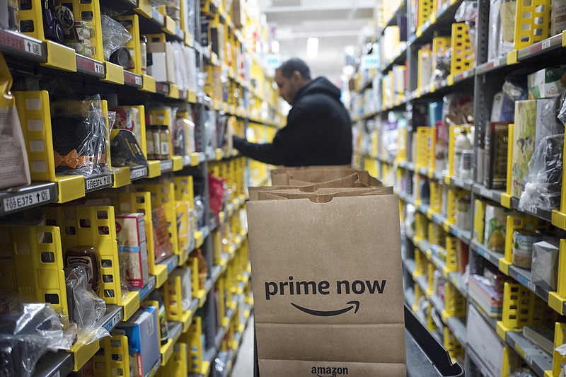 FILE - In this Dec. 20, 2017, file photo, a clerk reaches to a shelf to pick an item for a customer order at the Amazon Prime warehouse, in New York. Amazon says it is boosting the price of its monthly Prime membership fees for new and existing members by nearly 20 percent. The online retailer says its annual membership fee of $99 will not change.  (AP Photo/Mark Lennihan, File)