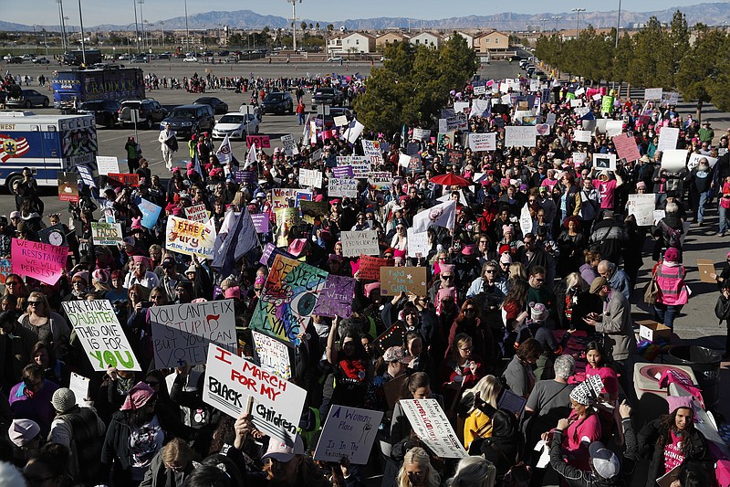 People wave flags and hold signs while entering a Women's March rally, Sunday, Jan. 21, 2018, in Las Vegas. (AP Photo/John Locher)