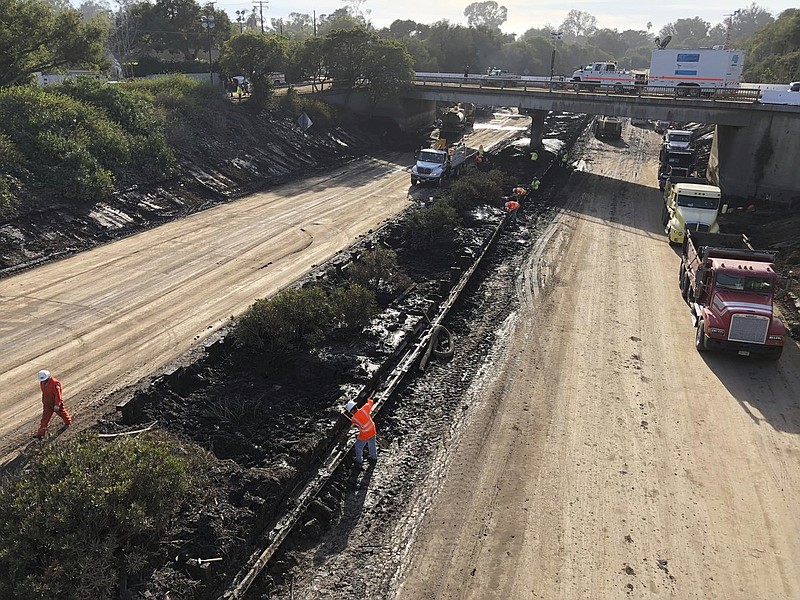 In this Wednesday, Jan. 17, 2018 photo Caltrans workers clear mud from a section of center divider guardrail along the northbound US 101 in Montecito in Montecito, Calif., that was closed following flooding on Jan. 9. California officials say key coastal highway swamped by deadly mudslides has reopened Sunday, Jan 21, 2018, after nearly 2-week closure. (Mike Eliason/Santa Barbara County Fire Department via AP, File)