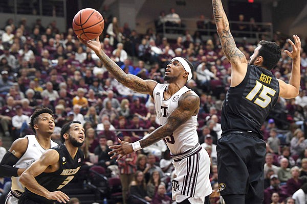 Texas A&M's Duane Wilson floats up a layup as Missouri's Jordan Geist defends during Saturday afternoon's game in College Station, Texas.