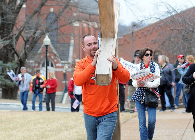 Jeremia Foote drags a large cross to the Capitol during a Saturday rally celebrating the first anniversary of President Donald Trump's inauguration. The event was coordinated by the Missouri Republican Leadership Initiative.