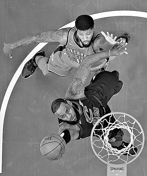Cleveland Cavaliers' LeBron James, center, drives to the basket against Oklahoma City Thunder's Paul George in the first half Saturday in Cleveland. 