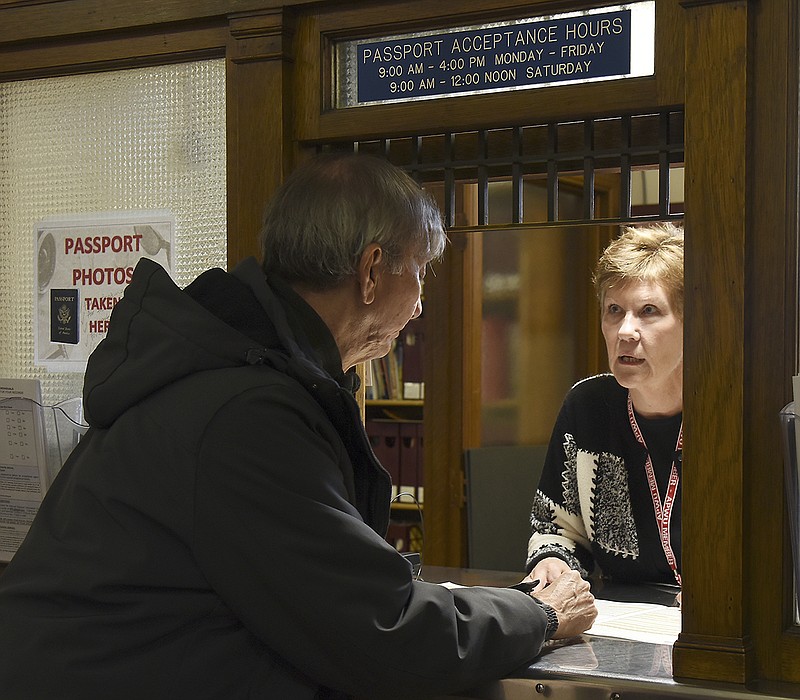 Postal Clerk April Burger, behind window, works with Passport customer Ed Gray at the main post office on W. High Street.