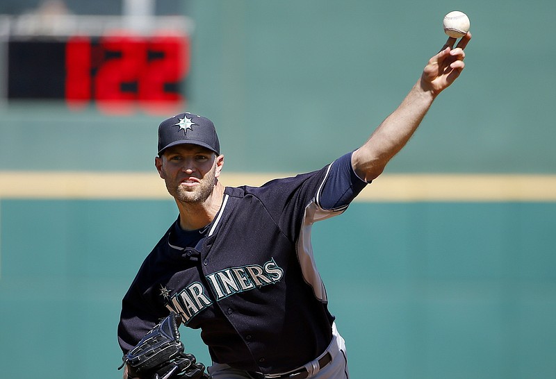 In this March 8, 2015, file photo, Seattle Mariners' J.A. Happ throws a pitch between innings as pitch clock counts down in the background during a spring training baseball game against the Cincinnati Reds in Goodyear, Ariz. Major League Baseball owners and executives meet this week in Beverley Hills, Calif.,, and will discuss whether to push ahead with pitch clocks and limits on mound visits despite opposition from players.  (AP Photo/Ross D. Franklin, File)