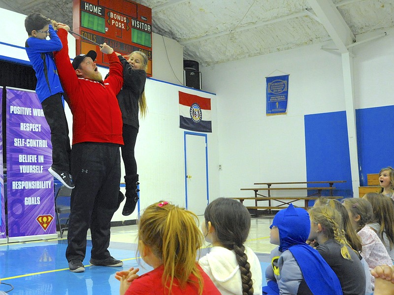 <p>Democrat photo/Michelle Brooks</p><p>Guiness World Record-holder J.D. “The Iceman” Anderson lifts Benton Althoff and Adalynn Robb above his head Feb. 2 during an assembly at High Point School.</p>