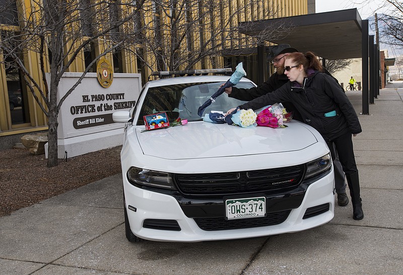 Michael Smart and Eleah Benton of Colorado Springs place flowers on a memorial outside the El Paso County Sheriff's Office in Colorado Springs, Colo., Tuesday, Feb. 6, 2018, for Deputy Micah Flick, who was killed when an investigation of a motor vehicle theft turned into a deadly shooting Monday outside a Colorado Springs apartment complex. Three other law enforcement officers were shot. The suspect was killed and one citizen injured. Smart and Benton didn't know the 34-year-old deputy but wanted to pay their respects. (Christian Murdock/The Gazette via AP)