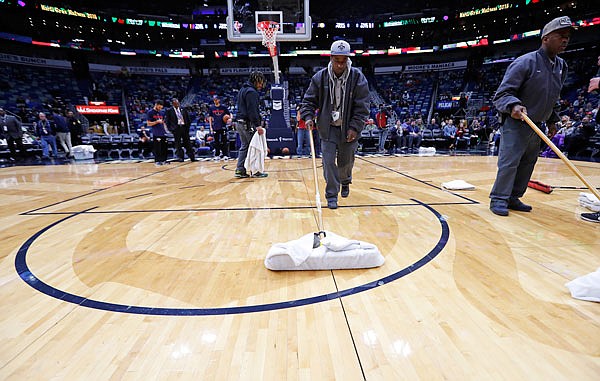 Workers mop the court Wednesday night during a delay at the start of an NBA game between the Pacers and the Pelicans in New Orleans. The game was eventually postponed due to a leak in the roof.