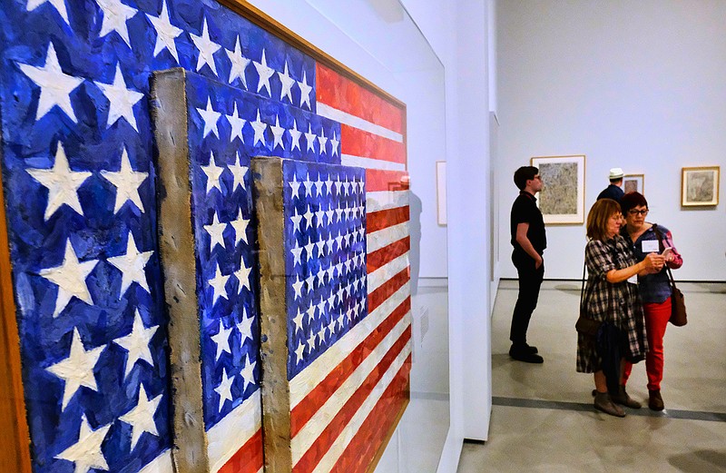 This Wednesday, Feb. 7, 2018 photo journalist gather around a Jasper Johns, Flag, encaustic and collage on canvas during a media preview at The Broad in Los Angeles. Jasper Johns 'Something Resembling Truth' is the first major survey of the artist's work to be shown in Los Angeles and will be on view at The Broad Feb. 10, 2018 through May 13, 2018. (AP Photo/Richard Vogel)