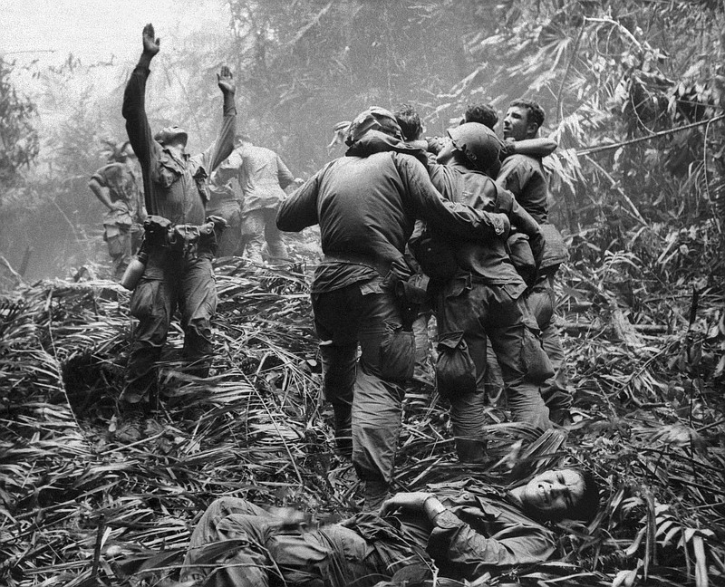 FILE - This April 1968 file photo shows the first sergeant of A Company, 101st Airborne Division, guiding a medevac helicopter through the jungle foliage to pick up casualties suffered during a five-day patrol near Hue, April 1968. Two soldiers in the photo, Dallas Brown, bottom, and Tim Wintenburg, far right, recently reunited to talk to The Associated Press about the iconic photo and the war. (AP Photo/Art Greenspon, File)