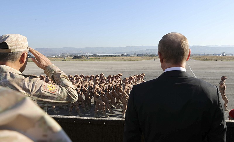 FILE - In this file photo taken on Tuesday, Dec. 12, 2017, Russian President Vladimir Putin, right, watches the troops marching as he and Syrian President Bashar Assad visit the Hemeimeem air base in Syria. Several private Russian military contractors were killed by a U.S. strike in Syria, Russian media reported Tuesday, Feb. 13, 2018 in a development that could further inflame Russia-U.S. tensions if officially confirmed. (Mikhail Klimentyev/Pool Photo via AP, File)