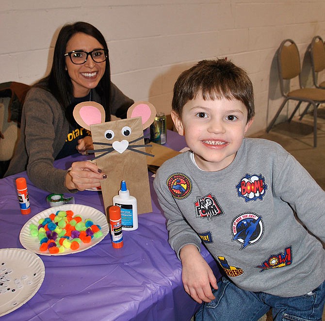 Ilana Holland clasps the mouse craft she helped Liam Qualls, 5, make. 