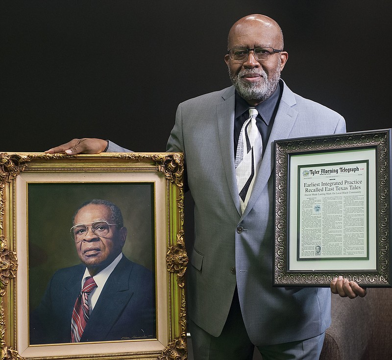 In this Feb. 2, 2018 photo, Richard Taliaferro, 69, holds a framed portrait and framed newspaper article about his father Dr. Theodore J. Taliaferro in Tyler, Texas. Taliaferro came to Tyler, Texas in 1939 to work as a general practitioner in northern part of the city where the black community reside. (Sarah A. Miller/Tyler Morning Telegraph via AP)
