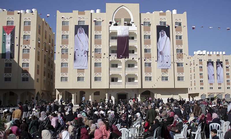 FILE - In this Jan. 16, 2016 photo, Palestinians gather at the Qatari-funded Hamad City housing complex in Khan Younis, southern Gaza Strip. Four years ago, Israel inflicted heavy damage on Gaza’s infrastructure during a bruising 50-day war with Hamas militants. Now, fearing a humanitarian disaster on its doorstep, Israel is appealing to the world to fund a series of big-ticket development projects in the war-torn area. The banners show Qatar's Emir, Sheikh Tamim bin Hamad Al Thani, left, and his father, Sheikh Hamad bin Khalifa Al Thani. (AP Photo/ Khalil Hamra, File)