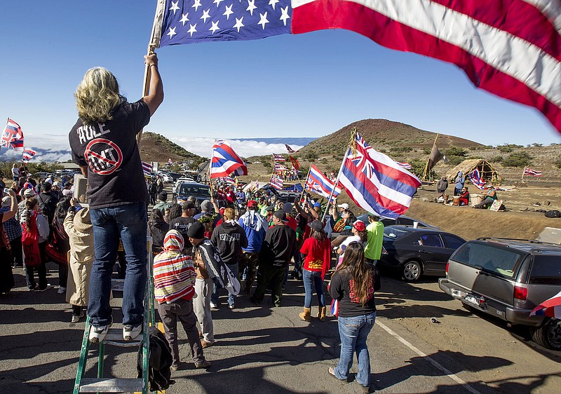 FILE - In this June 24, 2015 file photo, Thirty Meter Telescope protesters walk on a road during a blockade that prevented TMT construction vehicles from driving up to the summit of Mauna Kea near Hilo on the island of Hawaii in Hawaii. In a similar vein, Native Hawaiian activists, who claim to be descendants of Kauai's last king, are occupying the closed Coco Palms Hotel on the island of Kauai, saying they have documents giving them the rights to the land, and are protesting the rebuilding of the hotel, where Elvis Presley's character got married in the film "Blue Hawaii." It has been closed since a hurricane tore through it in 1992. (Holly Johnson/Hawaii Tribune-Herald via AP, File)