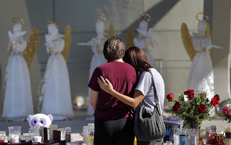 People comfort each other at a public memorial for the victims of the Wednesday shooting at Marjory Stoneman Douglas High School, in Parkland, Fla., Friday, Feb. 16, 2018. Nikolas Cruz, a former student, was charged with 17 counts of premeditated murder.  (AP Photo/Gerald Herbert)