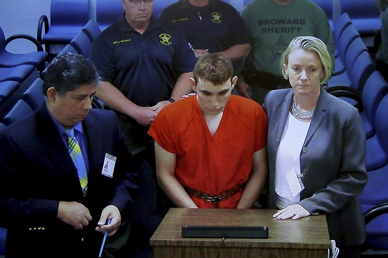 A video monitor shows school shooting suspect Nikolas Cruz, center, making an appearance before Judge Kim Theresa Mollica in Broward County Court, Thursday, Feb. 15, 2018, in Fort Lauderdale, Fla.  Cruz is accused of opening fire Wednesday at Marjory Stoneman Douglas High School in Parkland, Fla., killing more than a dozen people and injuring several.   (Susan Stocker/South Florida Sun-Sentinel via AP, Pool)
