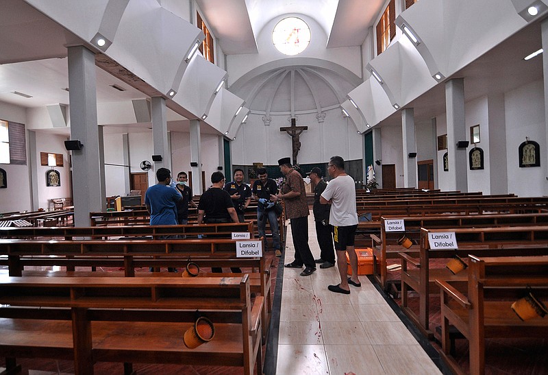 Police officers investigate inside St. Lidwina Church following an attack in Sleman, Yogyakarta province, Indonesia, Sunday, Feb. 11, 2018. Police shot a sword-wielding man who attack the church during a mass, injuring a number of people including a German priest. The reason for the attack Sunday morning was not immediately clear. (AP Photo/Slamet Riyadi)