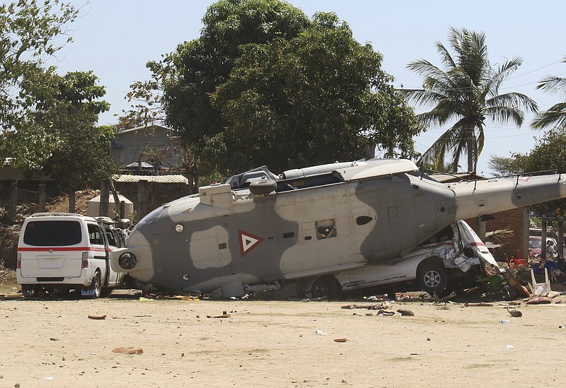 A downed helicopter lays in its side in Santiago Jimitepec, Saturday, Feb. 17, 2018. The military helicopter carrying officials assessing damage from the Friday's earth quake crashed killing 13 people and injuring 15, all of them on the ground. (AP Photo/Luis Alberto Cruz Hernandez)