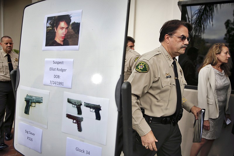 FILE - In this May 24, 2014 file photo, Santa Barbara County Sheriff Bill Brown, right, walks past a board displaying photos of gunman Elliot Rodger and the weapons he used in a mass shooting in Isla Vista, Calif., after a news conference in Santa Barbara, Calif. A growing number of states have passed laws or are considering bills allowing courts to temporarily remove guns from individuals deemed a danger to themselves or others, an intervention that advocates say stops shootings and suicides by disturbed individuals. (AP Photo/Jae C. Hong, File)