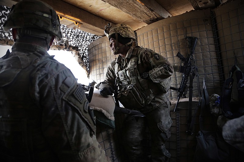 In this Friday, Jan. 26, 2018 photo, U.S. Army Sgt. Kaylin Jones, 25, stands at a guard tower on the perimeter of a small coalition outpost on the western edge of Iraq. A few hundred American troops are stationed at a small outpost near the town of Qaim along Iraq's border with Syria. Thousands of U.S. troops and billions of dollars spent by Washington helped bring down the Islamic State group in Iraq, but many of the divisions and problems that helped fuel the extremists’ rise remain. (AP Photo/Susannah George)