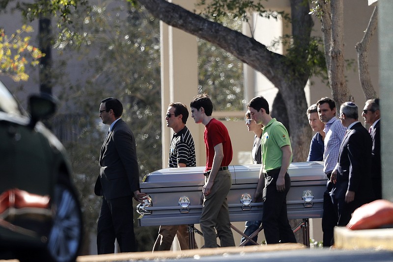 Pall bearers carry the casket of Scott Beigel after his funeral in Boca Raton, Fla., Sunday, Feb. 18, 2018. Beigel was a teacher at Marjory Stoneman Douglas High School in Parkland, who was killed along with 16 others in a mass shooting at the school on Wednesday.  Nikolas Cruz, a former student, was charged with 17 counts of premeditated murder. (AP Photo/Gerald Herbert)