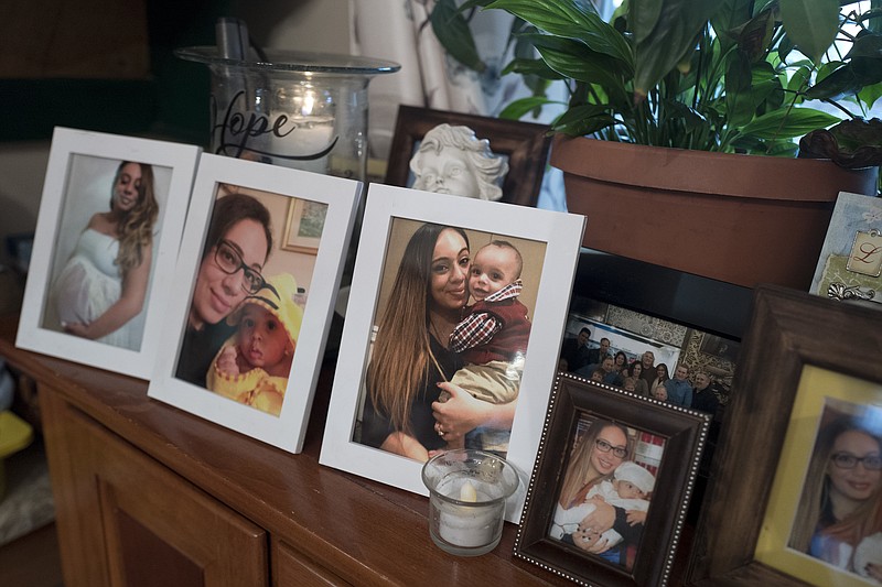 In this Feb. 9, 2018 photo, Chelsea Cobo holds her son, Christopher, in framed photos arranged as a shrine at her home in the Brooklyn borough of New York. Cobo disappeared in May of 2016. New DNA science developed to identify the skeletal remains of the 9/11 dead now serves another desperate need: helping families find long-missing loved ones, dead or alive. (AP Photo/Mark Lennihan)