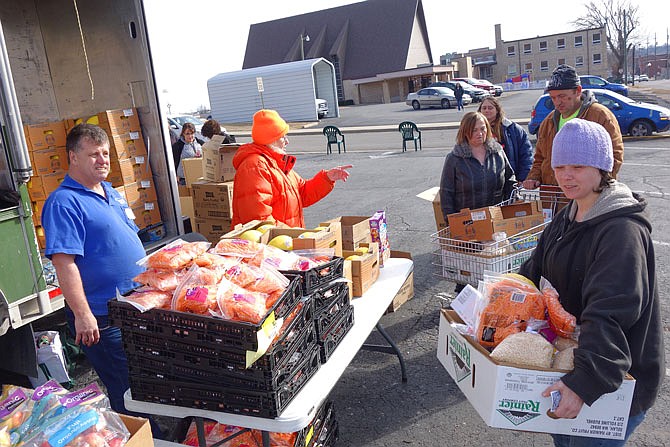 Volunteers pass out food Friday during a mobile food pantry's monthly stop at Court Street United Methodist Church. In April, church members hope to open a permanent food pantry at the church.