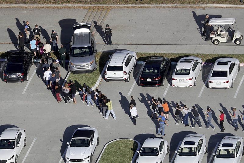 FILE - In this Feb. 14, 2018 file photo, students are evacuated by police from Marjory Stoneman Douglas High School in Parkland, Fla., after a shooter opened fire on the campus. (Mike Stocker/South Florida Sun-Sentinel via AP)