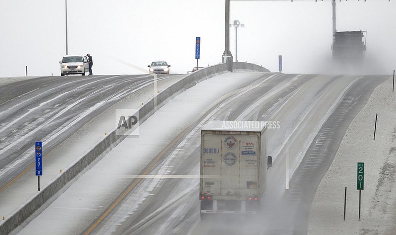 A motorist stops to clear ice from his wipers along I-70 near Lawrence, Kan., Tuesday, Feb. 20, 2018. The area is under a winter weather advisory.