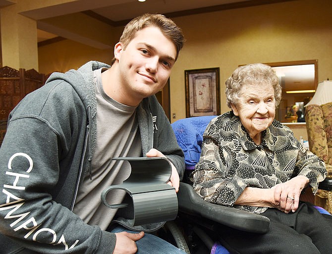 Dolores Forck, right, and her family are grateful for the capability of 3-D printers and Kaleb Tuinstra, left. He, along with another Mechatronics student at Nichols Career Center, designed the piece he's holding that helps prevent Forck's right arm from contracting to her chest. Forck suffered a stroke on her right side in November.