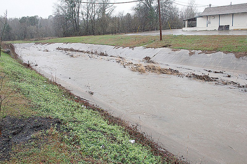  Fast-running water rises ever higher in the drainage ditch running north to south under New Boston Road on Wednesday near Big Jake's Barbecue and Burger King. Weather forecast calls for rain over the next few days, and a flood watch is in effect for much of the area.