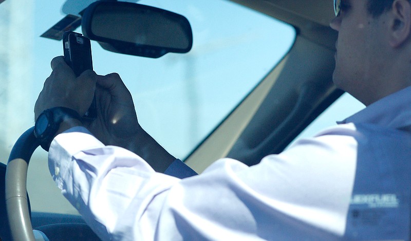A man looks at his phone July 16, 2015, while driving down Woodall Rodgers Freeway in Dallas.