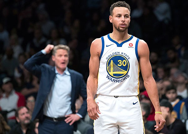 In this Nov. 19, 2017, file photo, Warriors guard Stephen Curry stands on the court as coach Steve Kerr gestures during a game against the Nets in New York.