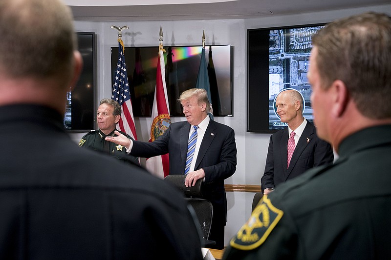 In this Feb. 16, 2018, photo, President Donald Trump, center, accompanied by Broward County Sheriff Scott Israel, left, and Florida Gov. Rick Scott, right, speaks as they meet with law enforcement officers at Broward County Sheriff's Office in Pompano Beach, Fla., following the shooting at Marjory Stoneman Douglas High School, in Parkland, Fla. Once again, it was the images of children that propelled Trump to act. Trump spent the first days after the Valentine’s Day school shooting that left 17 dead fixated on the traumatized students _ and parents _ spilling out their grief and anguish in Parkland, Florida. (AP Photo/Andrew Harnik)