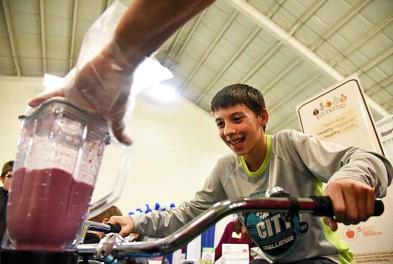 Derek Heees, 13, energetically rides a workout bike Saturday to simultaneously grind up a fruit smoothie during the Wellness Expo at the Jefferson City Area YMCA. 