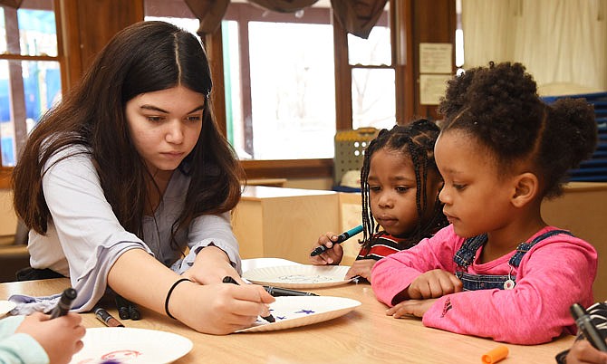 Maddi Schumer, left, assists Dream Dowdy, right, and Kaiveon Terrill, as they work on a paper snake Thursday at Cole County Head Start. Schumer is one of several students from the Jefferson City Academic Center who visited the preschool to read and interact with the young students.