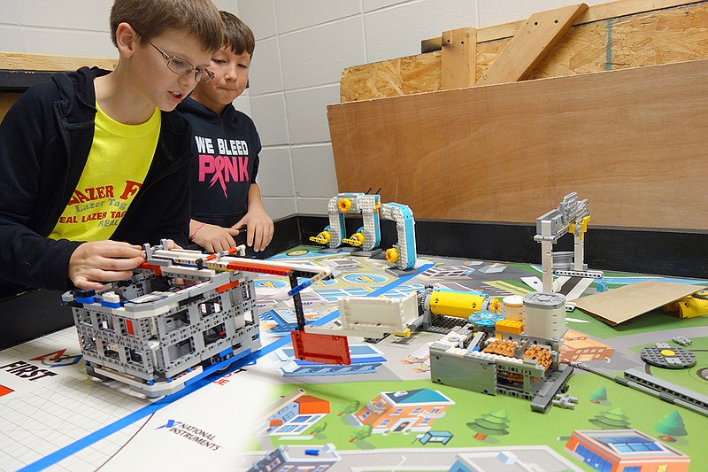 Eldon Upper Elementary RoboH20 team member Luke Graham demonstrates the extending arm of the team's robot as Braden Wrye helps describe the operation. The Gearheads after-school robotics program teaches children analytical thinking, creative problem and technological expertise. 