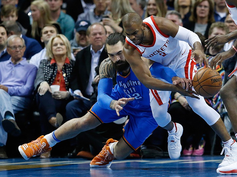 Oklahoma City Thunder center Steven Adams, left, reaches to in to knock the ball away from Houston Rockets guard Chris Paul, right, in the first half of an NBA basketball game in Oklahoma City, Tuesday, March 6, 2018. (AP Photo/Sue Ogrocki)