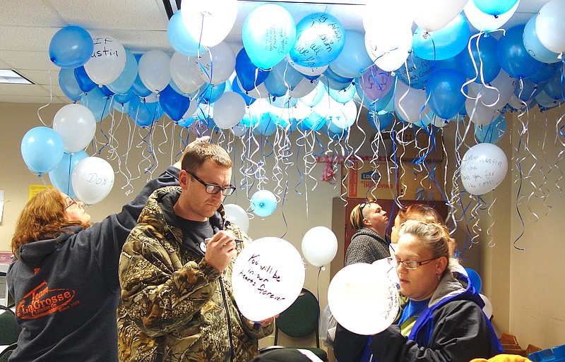 Joe Anderson, left, one of Dustin Anderson's brothers, writes a message on a balloon to be released Tuesday. He's launched an online fundraiser for his brother's cremation expenses.