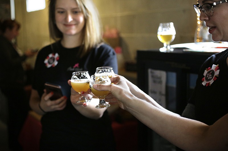 In this Sunday, March 4, 2018, photo, Heather Merson, of Danielson, Conn., left, and Shannon Jutras, of Foster, R.I., right, president of Quiet Corner Home Brew Club, raise their glasses in a toast after helping brew a batch of beer at Black Pond Brews brewery, in Danielson, Conn.