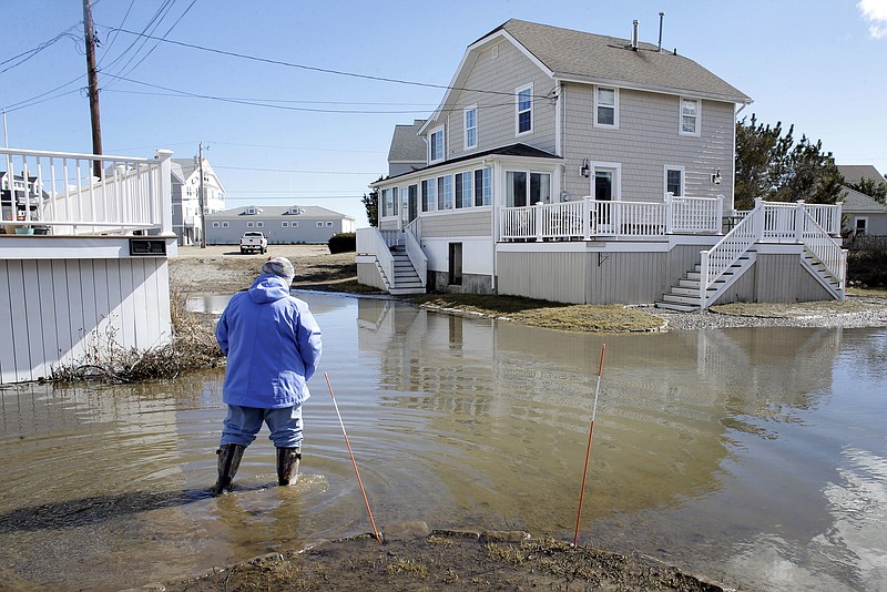 A resident of Duxbury, Mass., views flooding near her home, Sunday, March 11, 2018, in Duxbury. The Northeast is bracing for its third nor'easter in fewer than two weeks. The National Weather Service reports Sunday that a southern storm is expected to make its way up the coast causing more snowfall. (AP Photo/Steven Senne)